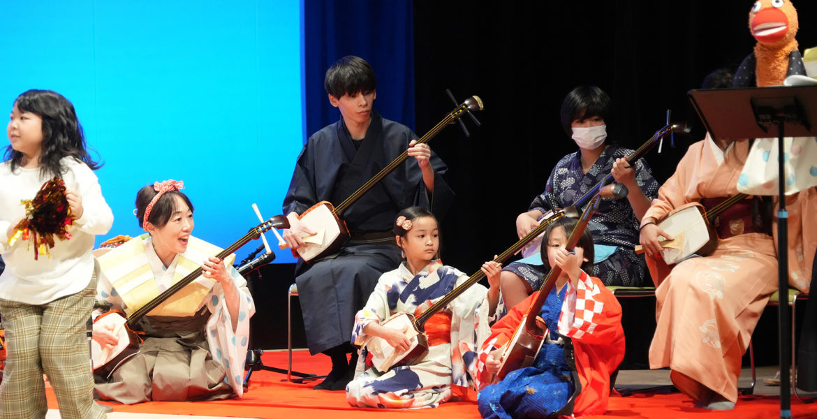 舞台で子どもたちと三味線を体験する様子