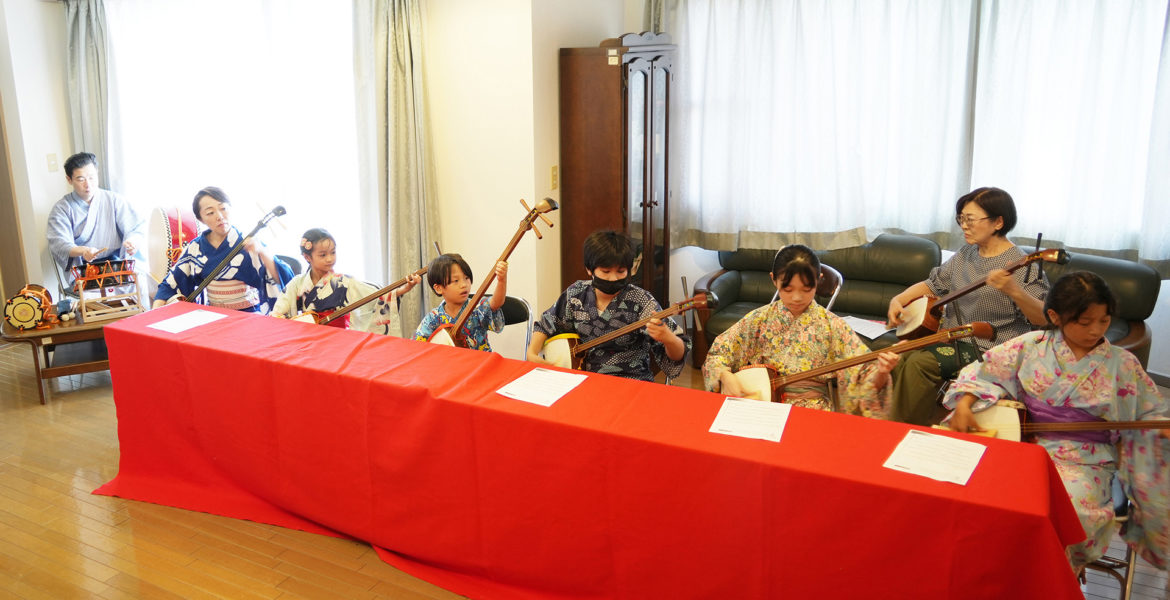 稽古場で複数人が三味線を演奏する様子