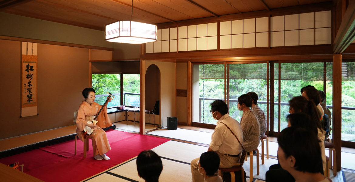 和室で観客に向けて三味線を演奏する山尾麻耶